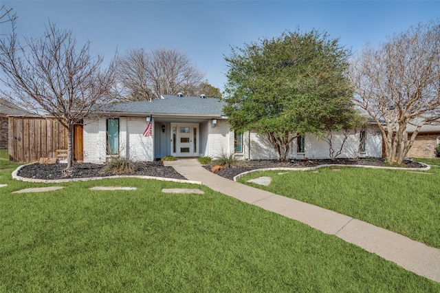 view of front of house with a front yard, brick siding, and roof with shingles