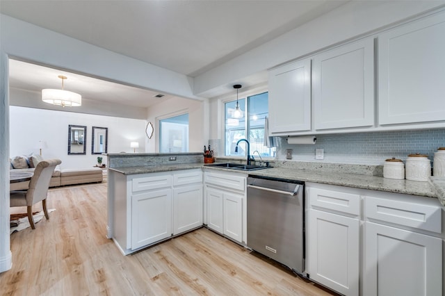 kitchen featuring light wood-style flooring, a sink, decorative light fixtures, stainless steel dishwasher, and a peninsula