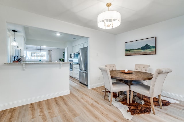 dining area with light wood finished floors and baseboards