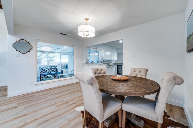 dining area featuring visible vents, baseboards, and light wood finished floors