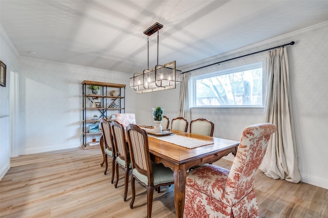 dining space with light wood-style flooring, crown molding, and baseboards