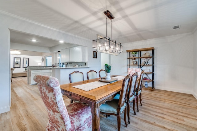 dining room with visible vents, crown molding, baseboards, light wood-style flooring, and an inviting chandelier