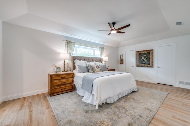 bedroom featuring visible vents, a raised ceiling, and light wood-style flooring