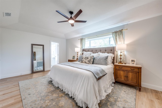 bedroom featuring baseboards, visible vents, ceiling fan, a raised ceiling, and light wood-type flooring