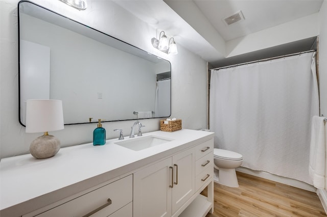 bathroom featuring visible vents, toilet, wood finished floors, a shower with shower curtain, and vanity