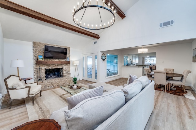 living room featuring visible vents, a chandelier, beam ceiling, a stone fireplace, and wood finished floors