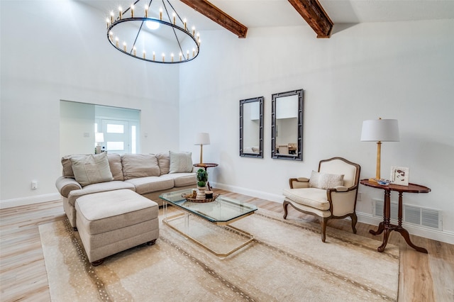 living room featuring beam ceiling, visible vents, baseboards, and wood finished floors