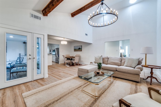 living room featuring wood finished floors, visible vents, beam ceiling, french doors, and a towering ceiling