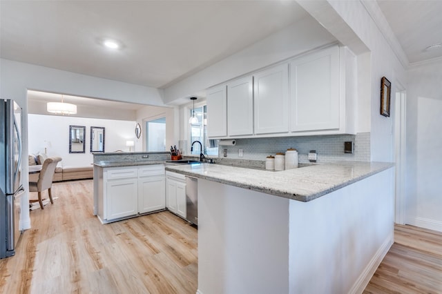 kitchen with white cabinetry, a peninsula, appliances with stainless steel finishes, and a sink