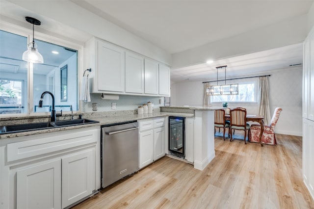 kitchen with a sink, wine cooler, white cabinets, light wood-style floors, and stainless steel dishwasher