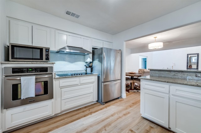 kitchen featuring visible vents, under cabinet range hood, appliances with stainless steel finishes, white cabinetry, and backsplash