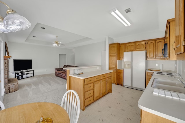 kitchen with visible vents, black microwave, light countertops, white fridge with ice dispenser, and a raised ceiling