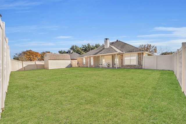 back of property with an outdoor structure, a lawn, brick siding, and a fenced backyard