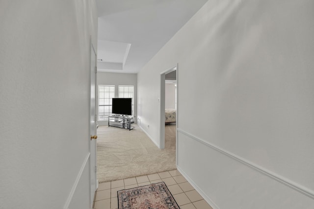 hallway with light tile patterned floors, light colored carpet, and baseboards