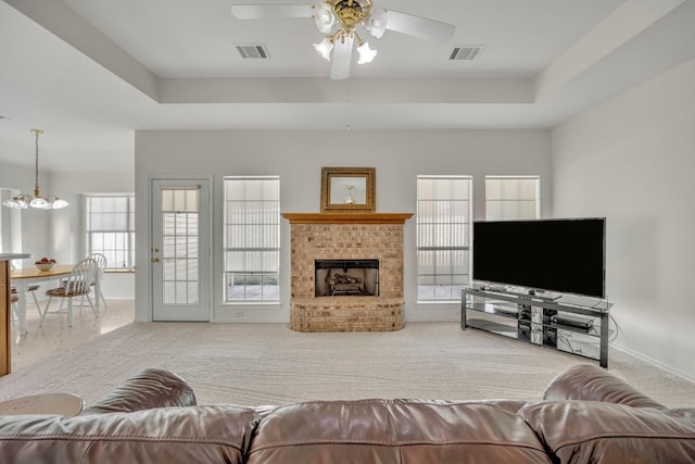 living room featuring a raised ceiling, a fireplace, and visible vents