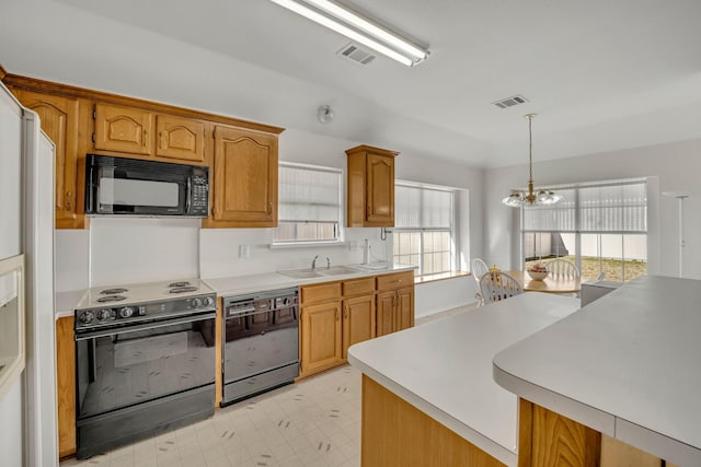 kitchen with a sink, visible vents, black appliances, and a chandelier