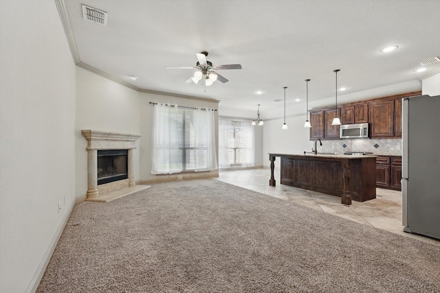 unfurnished living room featuring visible vents, ceiling fan, light colored carpet, ornamental molding, and a fireplace