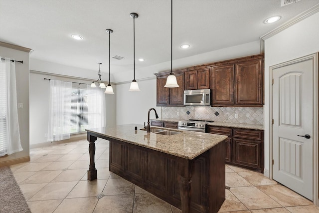 kitchen with light stone countertops, a center island with sink, a sink, stainless steel appliances, and tasteful backsplash