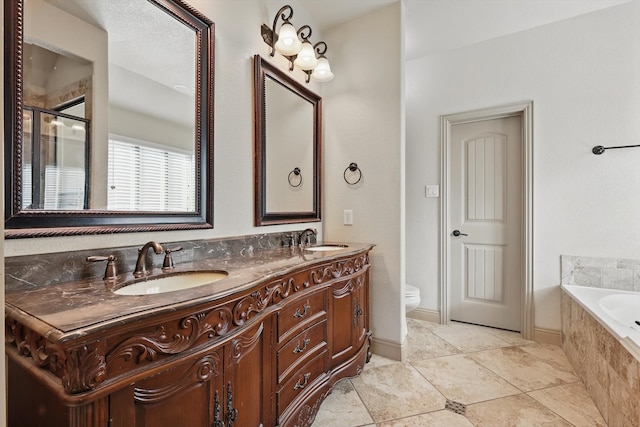 bathroom featuring double vanity, toilet, a garden tub, and a sink