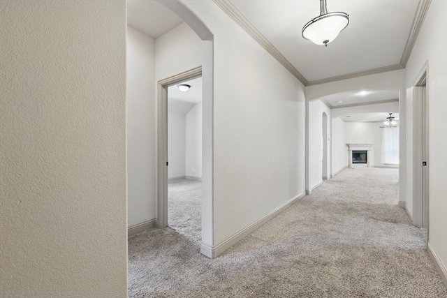 hall with baseboards, carpet floors, arched walkways, ornamental molding, and a textured wall