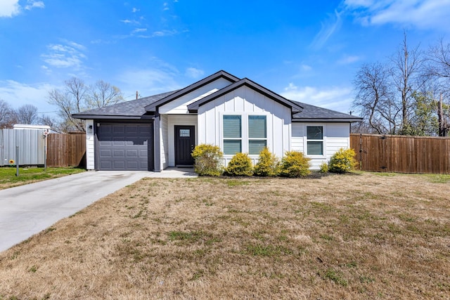 view of front of home with driveway, fence, board and batten siding, a front yard, and a garage