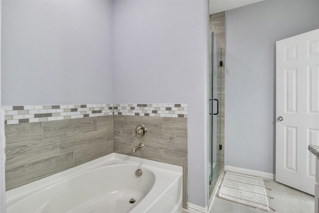 bathroom featuring a bath, a shower stall, and baseboards