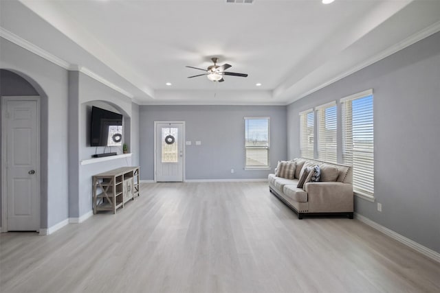 living room with baseboards, a raised ceiling, and light wood-style floors