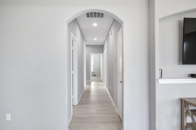 corridor featuring visible vents, recessed lighting, arched walkways, light wood-style floors, and baseboards