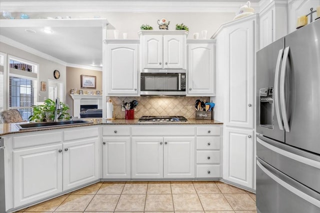 kitchen with a sink, ornamental molding, stainless steel appliances, white cabinetry, and tasteful backsplash