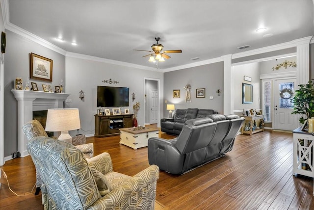 living area with visible vents, a ceiling fan, wood finished floors, a fireplace, and crown molding