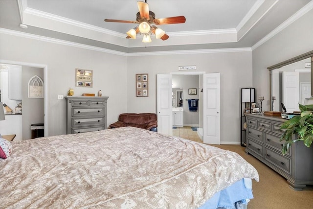 bedroom with a tray ceiling, light colored carpet, ornamental molding, and ensuite bathroom