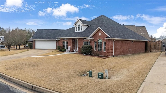 view of front of house with a garage, fence, brick siding, and driveway