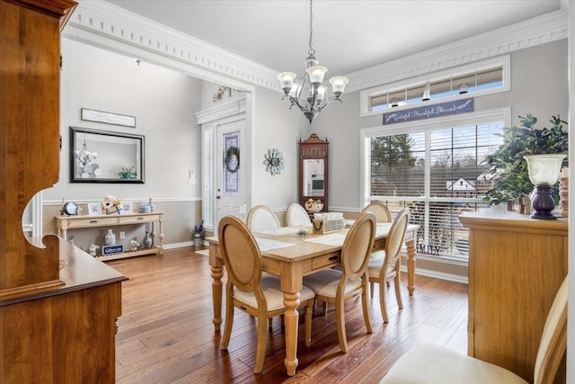 dining space with baseboards, a notable chandelier, hardwood / wood-style floors, and ornamental molding