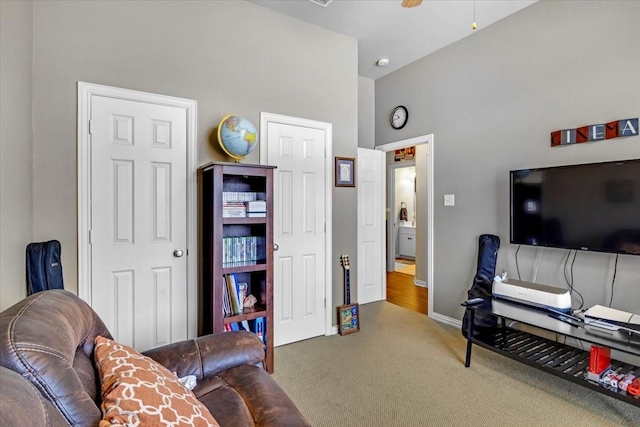 living area featuring ceiling fan, baseboards, and carpet