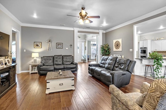 living room with visible vents, baseboards, dark wood-type flooring, and ornamental molding