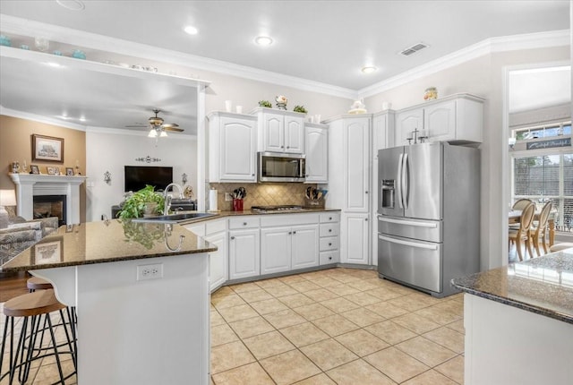 kitchen featuring a breakfast bar area, visible vents, a peninsula, a sink, and appliances with stainless steel finishes