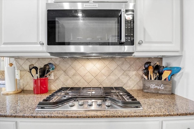 kitchen with tasteful backsplash, white cabinets, stainless steel appliances, and light stone counters