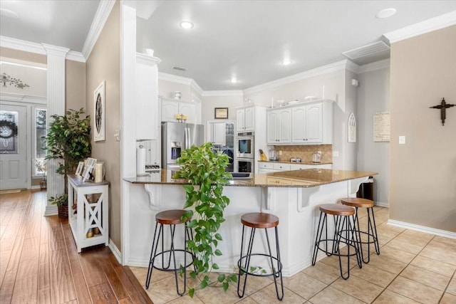 kitchen featuring dark stone countertops, a kitchen breakfast bar, a peninsula, and appliances with stainless steel finishes