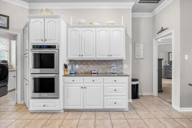 kitchen featuring dark stone countertops, backsplash, double oven, light tile patterned flooring, and white cabinets