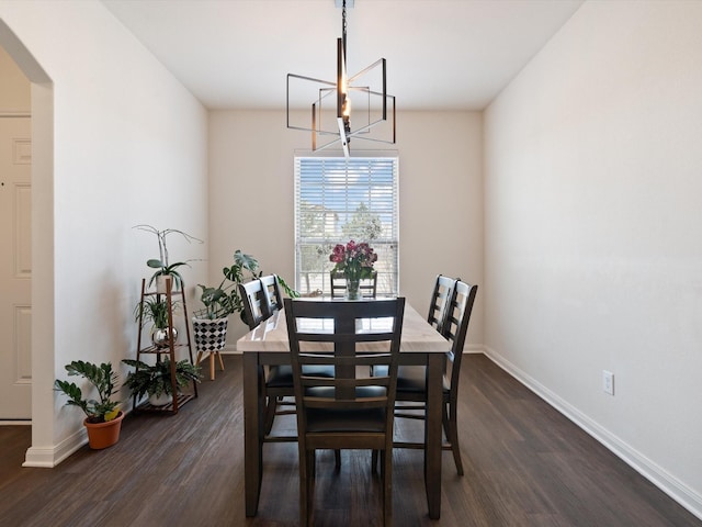 dining space with arched walkways, an inviting chandelier, dark wood-type flooring, and baseboards