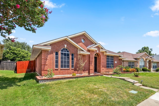 ranch-style house with a front lawn, fence, and brick siding