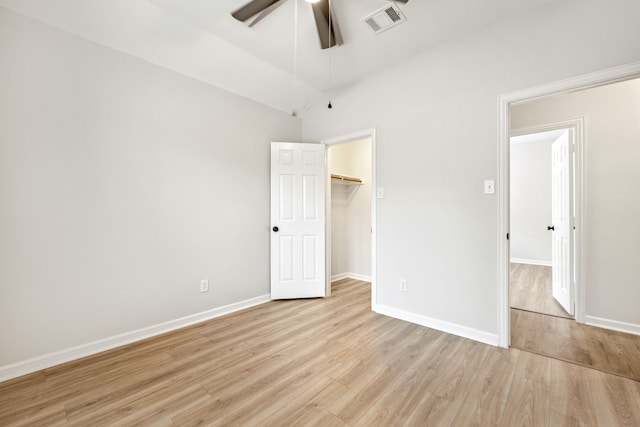 unfurnished bedroom featuring visible vents, baseboards, light wood-style floors, and vaulted ceiling