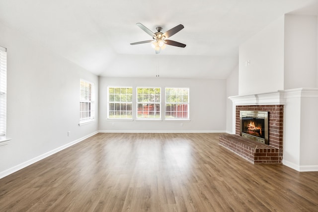 unfurnished living room with baseboards, wood finished floors, a fireplace, and vaulted ceiling