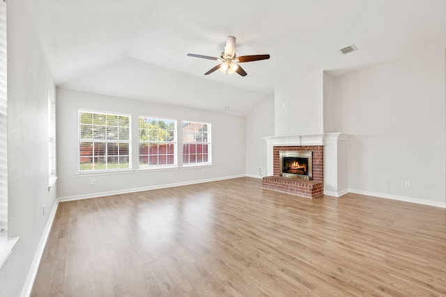 unfurnished living room with light wood-type flooring, visible vents, a brick fireplace, and ceiling fan