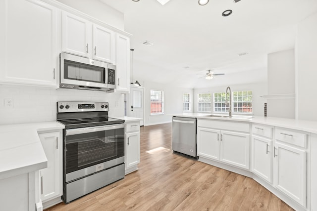 kitchen with visible vents, light wood finished floors, a sink, appliances with stainless steel finishes, and tasteful backsplash