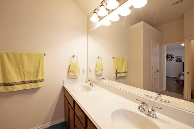 bathroom featuring baseboards, a sink, visible vents, and double vanity