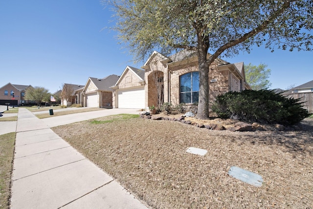 view of front facade with brick siding, driveway, a residential view, and a garage