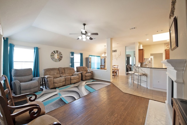 living room with ceiling fan, lofted ceiling, visible vents, and light wood finished floors