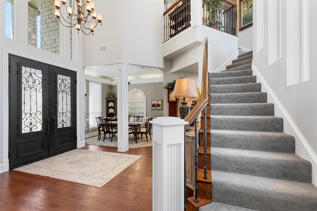 foyer featuring visible vents, wood finished floors, french doors, decorative columns, and stairs