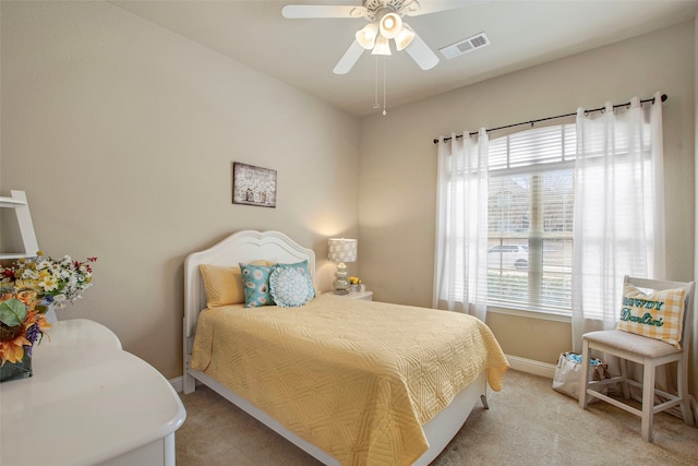 bedroom with visible vents, light colored carpet, baseboards, and ceiling fan